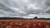 Dramatic clouds over Iceland mountains and red meadow Time lapse
