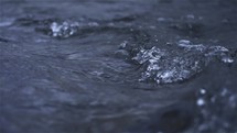 Slow motion of water splashing in dark river stream
