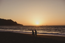 a couple walking on the beach at sunset