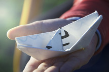 child holding a paper boat 