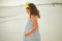 a young girl on a beach in a sundress 
