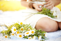 a woman sitting on a blanket with daisies 