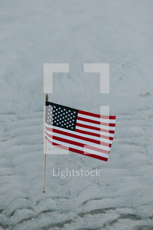 American flag in the sand on a beach 