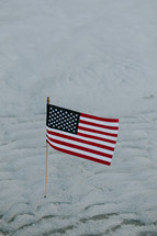 American flag in the sand on a beach 