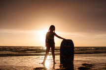 a girl with a boogie board on a beach 