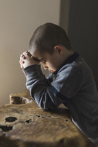 Little boy with his head down praying.