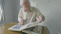 Senior caucasian man looking through an old photo album themes of memories nostalgia photos retired