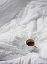 mug of cappuccino on a bed 