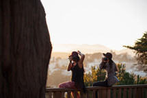 women sitting on a balcony taking pictures 