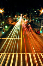 A long exposure photo taken of cars driving along a road in New York City.