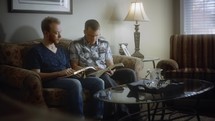 father and adult son reading a Bible together 