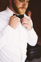 a man fixing his bow tie 
