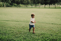a toddler boy running barefoot in the grass 