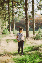a woman standing alone outdoors in a forest 