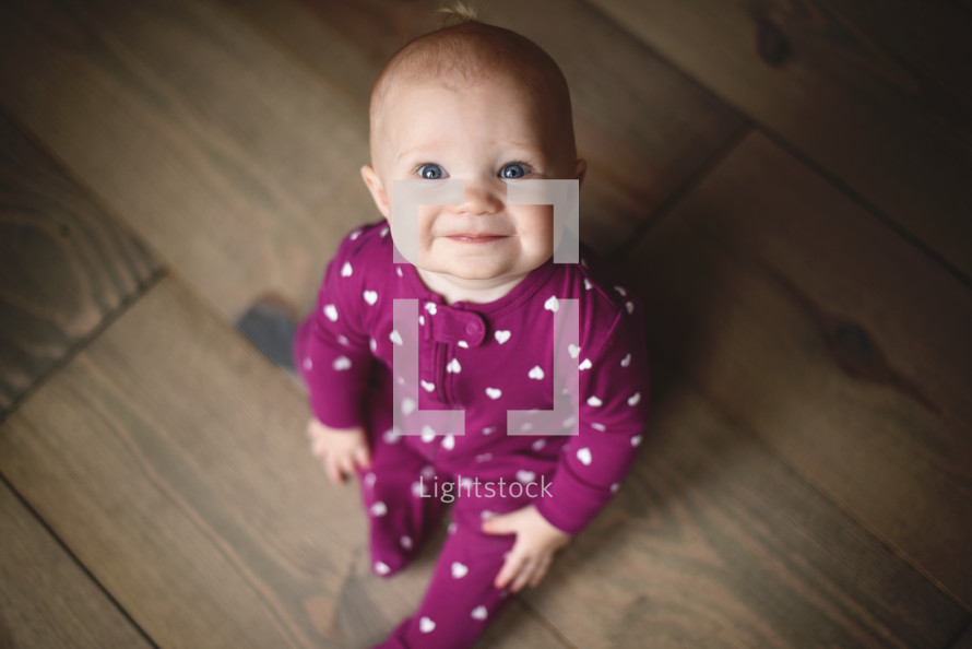 a smiling infant in heart pattern pajamas 