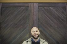 smiling man standing in front of wood doors