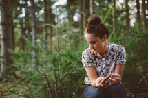 woman alone sitting in a forest thinking 