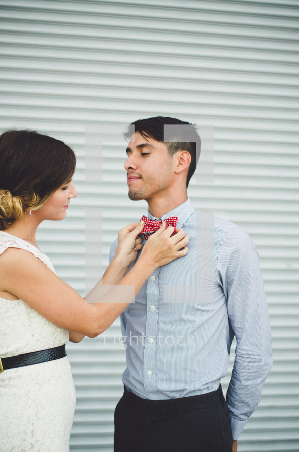 a woman adjusting a man's bow tie 