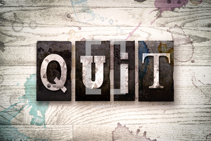 word quit on a white wash wood background 