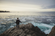 woman standing on a rock near the ocean