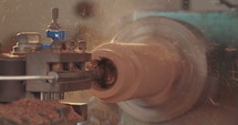 Slow motion macro shot of a man working on a wood lathe creating art.