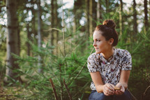 a woman sitting alone in a forest in thought 