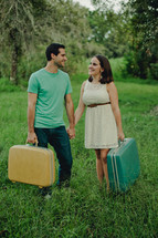 a couple standing outdoors holding suitcases 