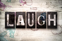 word laugh on white washed wood