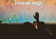 Silhouette of audience with hands raised at a Christian conference.