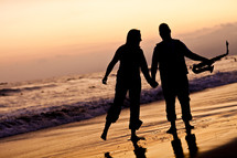 silhouette of a man and a woman holding hands on a beach holding a saxophone 