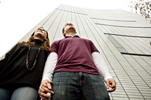 Couple holding hands in front of skyscraper building