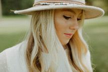 a blonde woman in a hat standing outdoors 