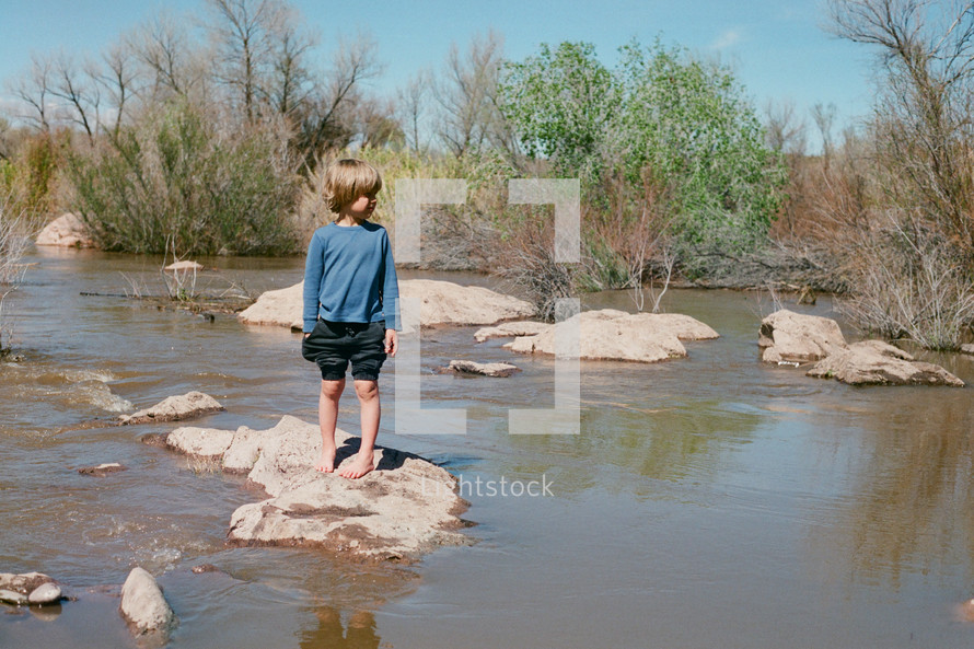 boy standing on a rock in stream 