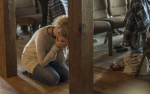 a young woman kneeling in prayer in the aisle of a church 