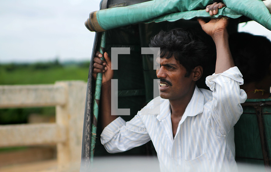 man in India riding on the back of a truck 