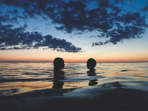 kids swimming in water at sunset 