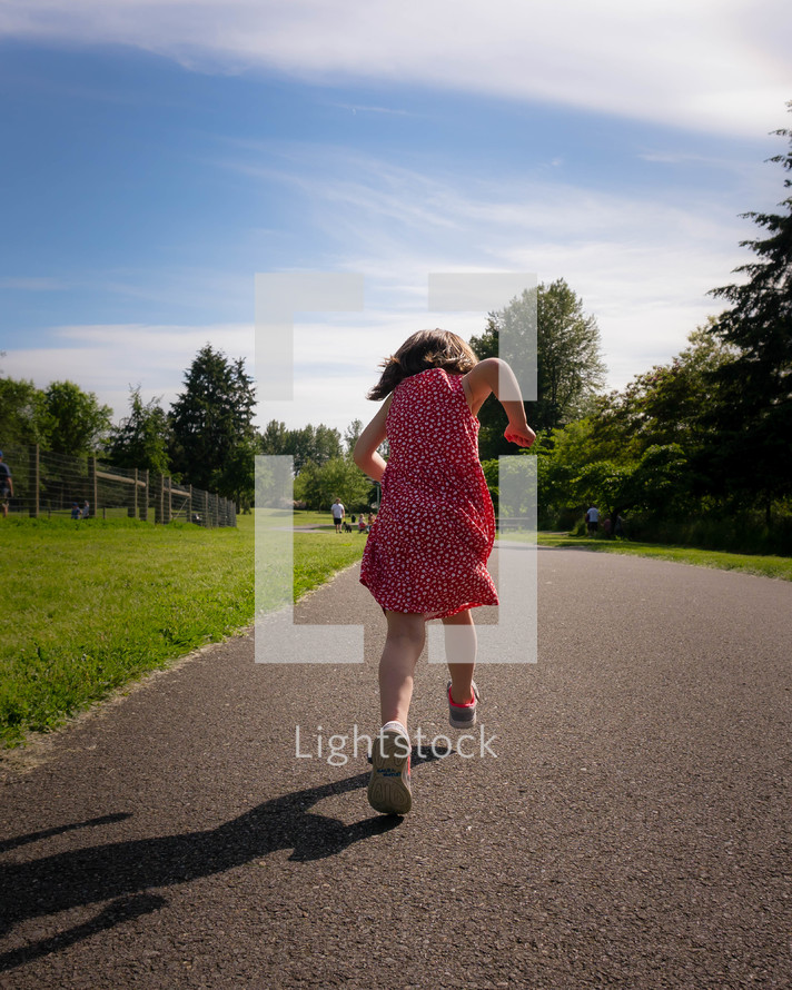 little girl running on a paved path 