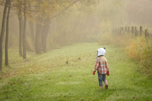 a child in a beanie and plaid shirt exploring rural countryside 