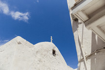 An old white stucco church against a blue sky.