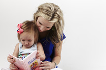 mother reading a children's bible to her toddler daughter