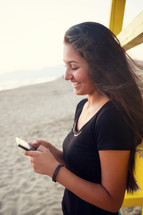 teenager while using the smartphone on the beach