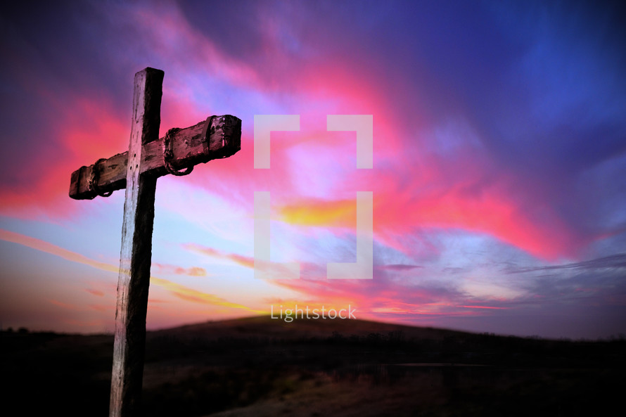 A cross under a pink and purple sky at sunrise 