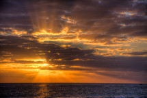 sunburst through the clouds at sunset over the ocean