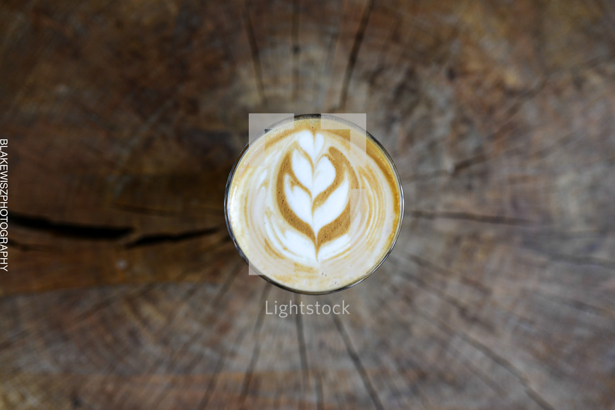 A cup of latte' on a tree stump.