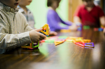 children playing with magnetic toys on a wood table 