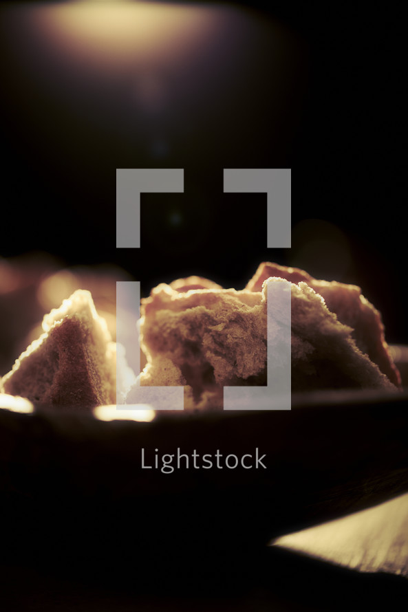 A light shines on pieces of bread in a bowl.