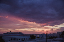 A cruise ship near a Greek city at sunset.