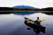a man rowing a canoe on a lake 