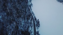 aerial view over a car traveling on a road in snow 