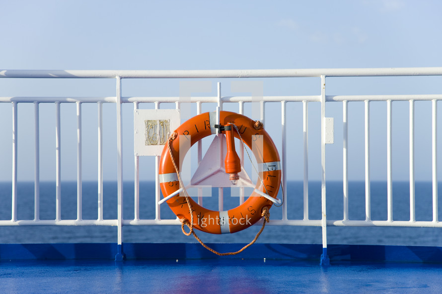 A life preserver hanging on the railing at the end of a ship